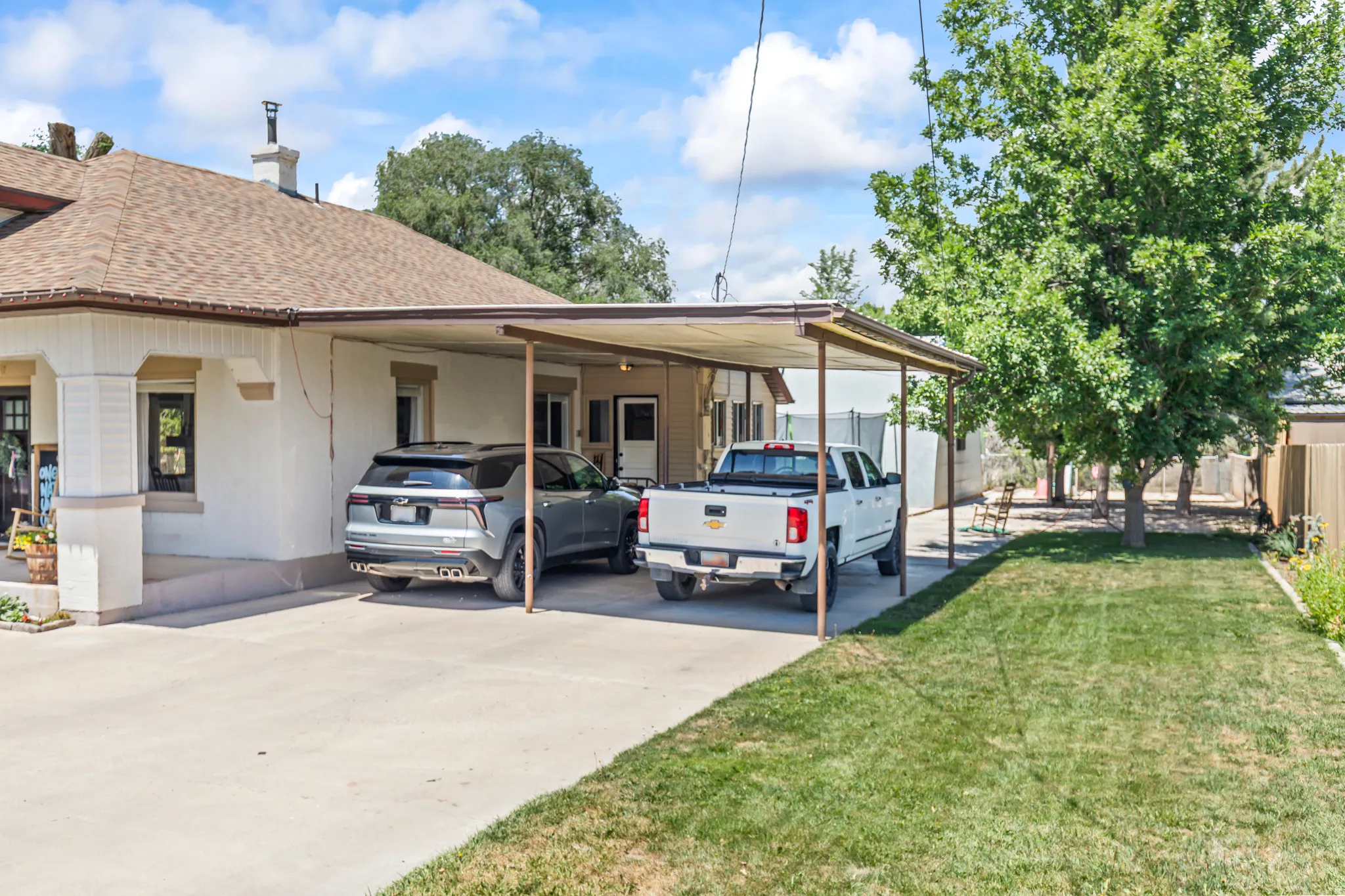 Expansive concrete driveway featuring a double carport