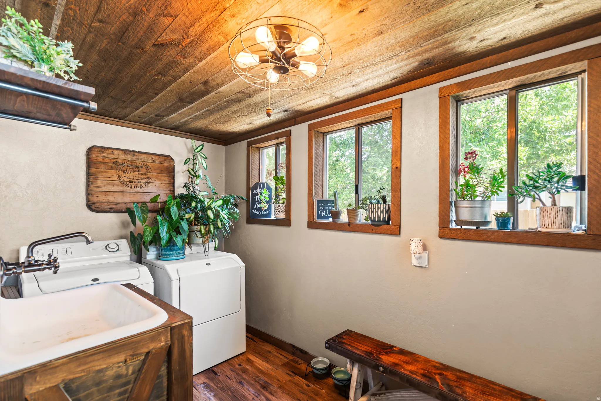 Laundry area featuring a large utility sink with a wall-mounted faucet, wood-finish flooring, and a natural wood plank ceiling