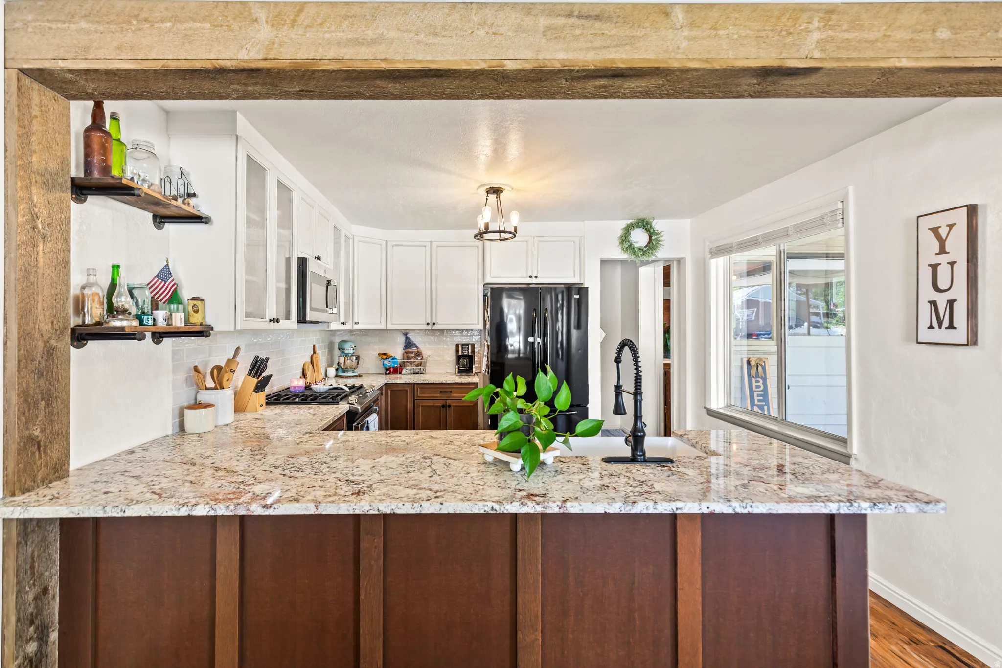 Kitchen featuring a two-tone cabinetry design, light-toned countertops, tile backsplash, and a black faucet