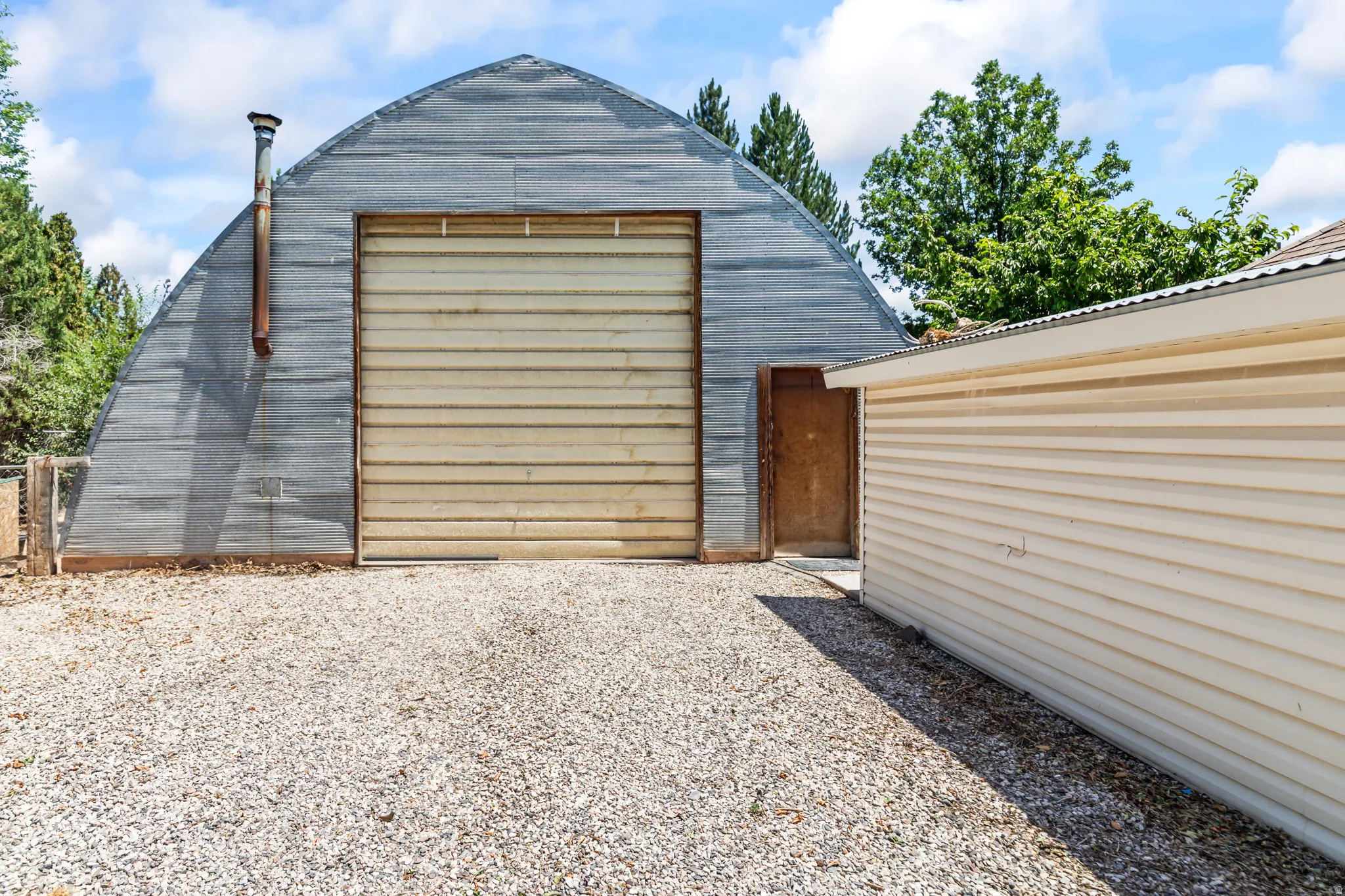 Quonset hut structure featuring a corrugated metal exterior and a metal roll-up door