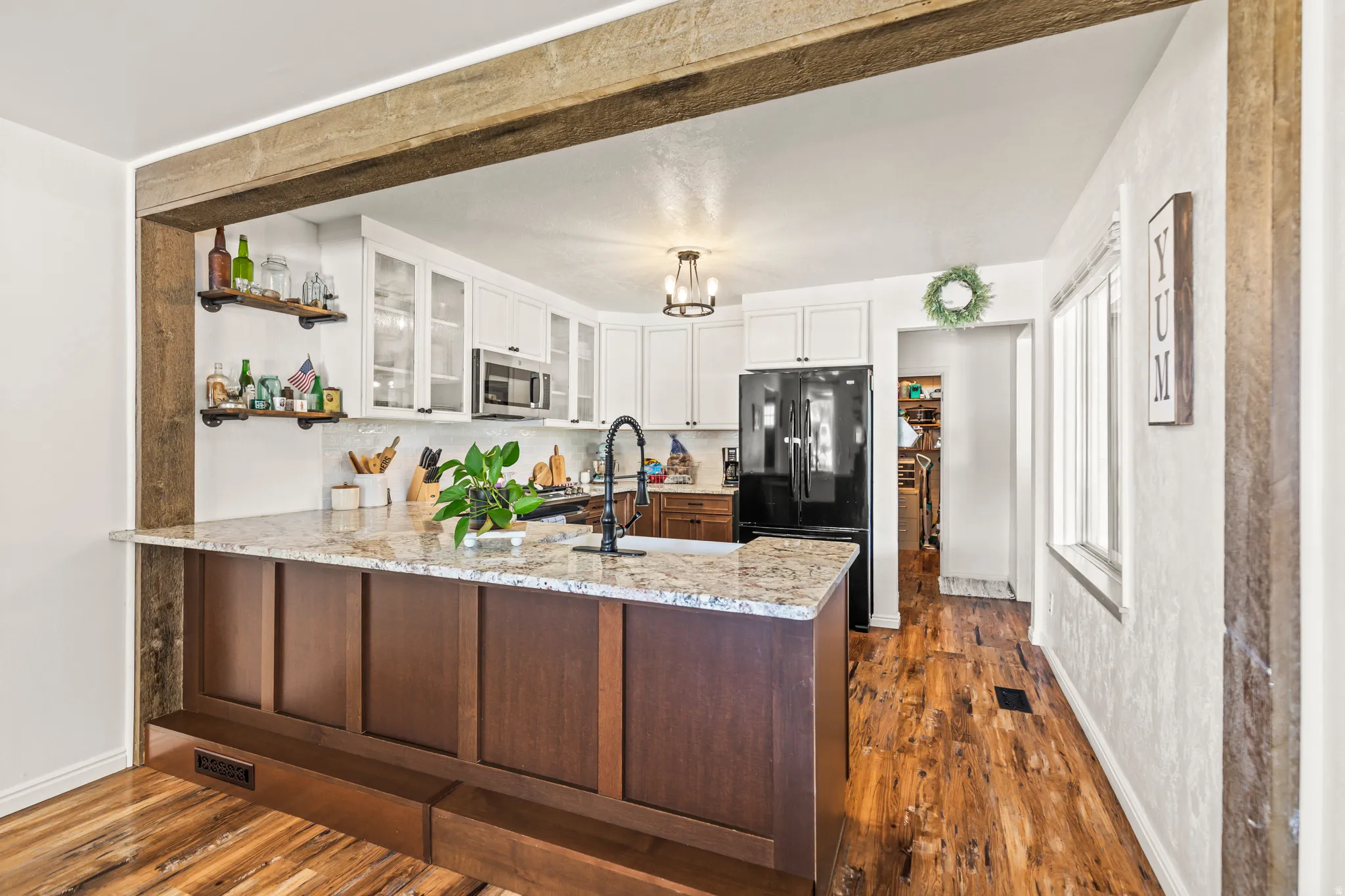 Kitchen featuring a multi-tone island with a light-toned countertop, a black faucet, and white upper cabinetry