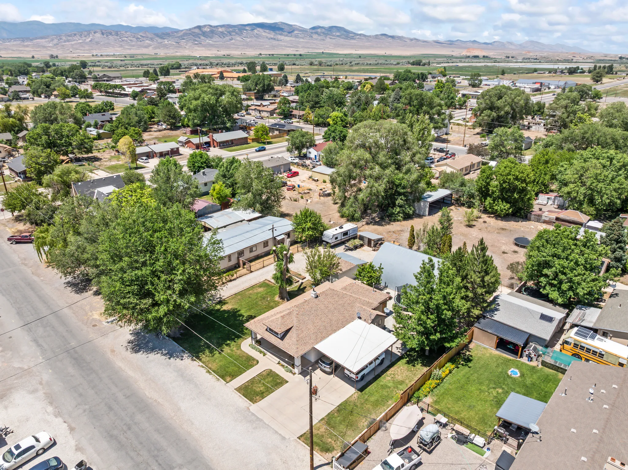 Aerial perspective showcasing a residential property with a brown shingle roof and a white carport