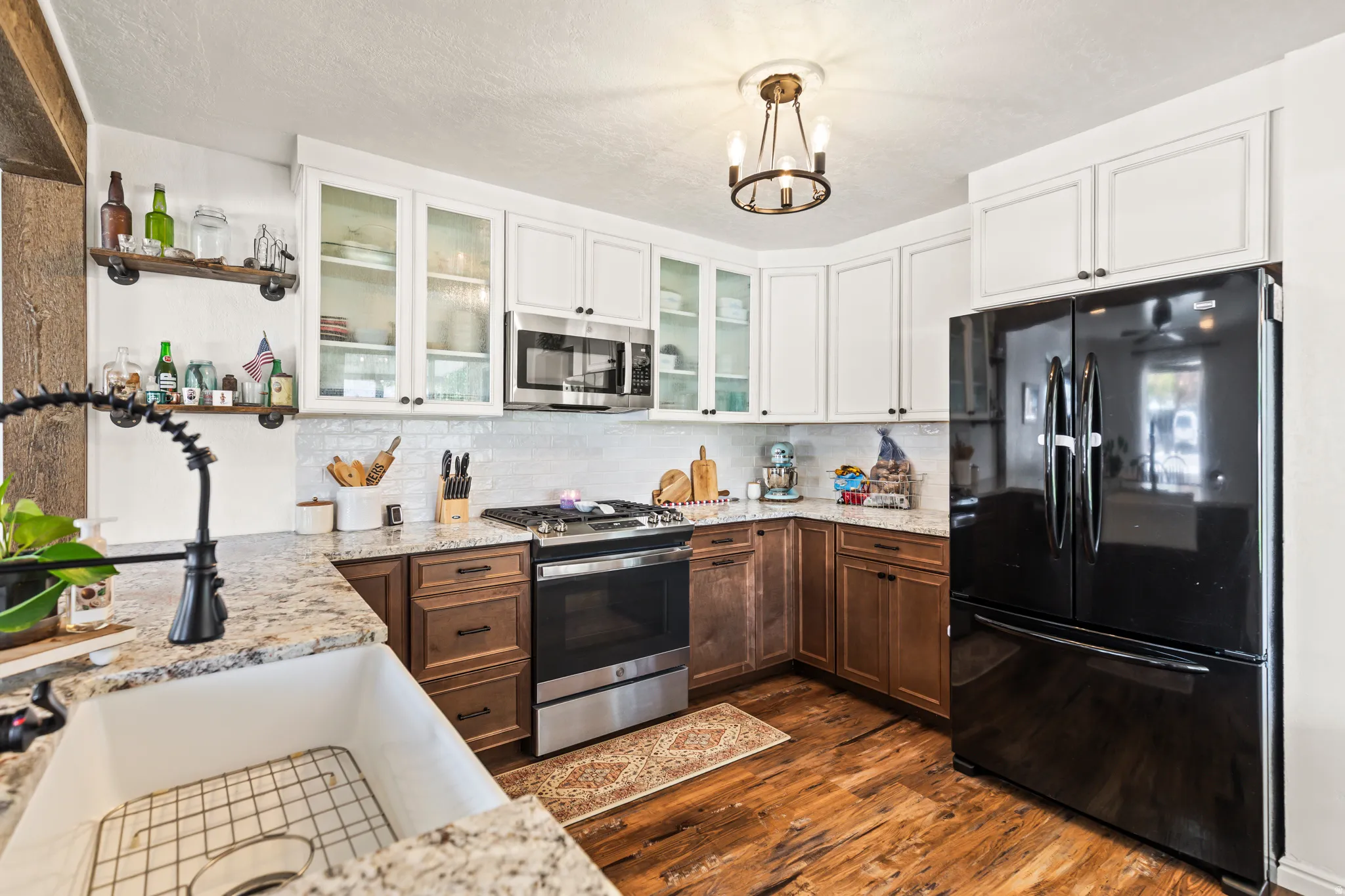 Kitchen featuring granite countertops, wood-finish flooring, and a white farmhouse sink with a matte black faucet