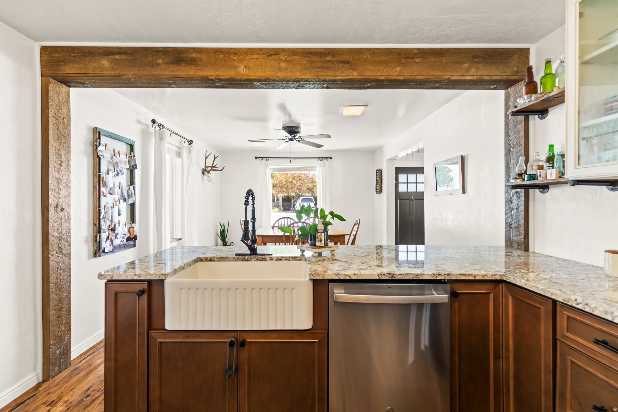 Kitchen island with granite countertops, a white apron-front sink, and stainless steel dishwasher