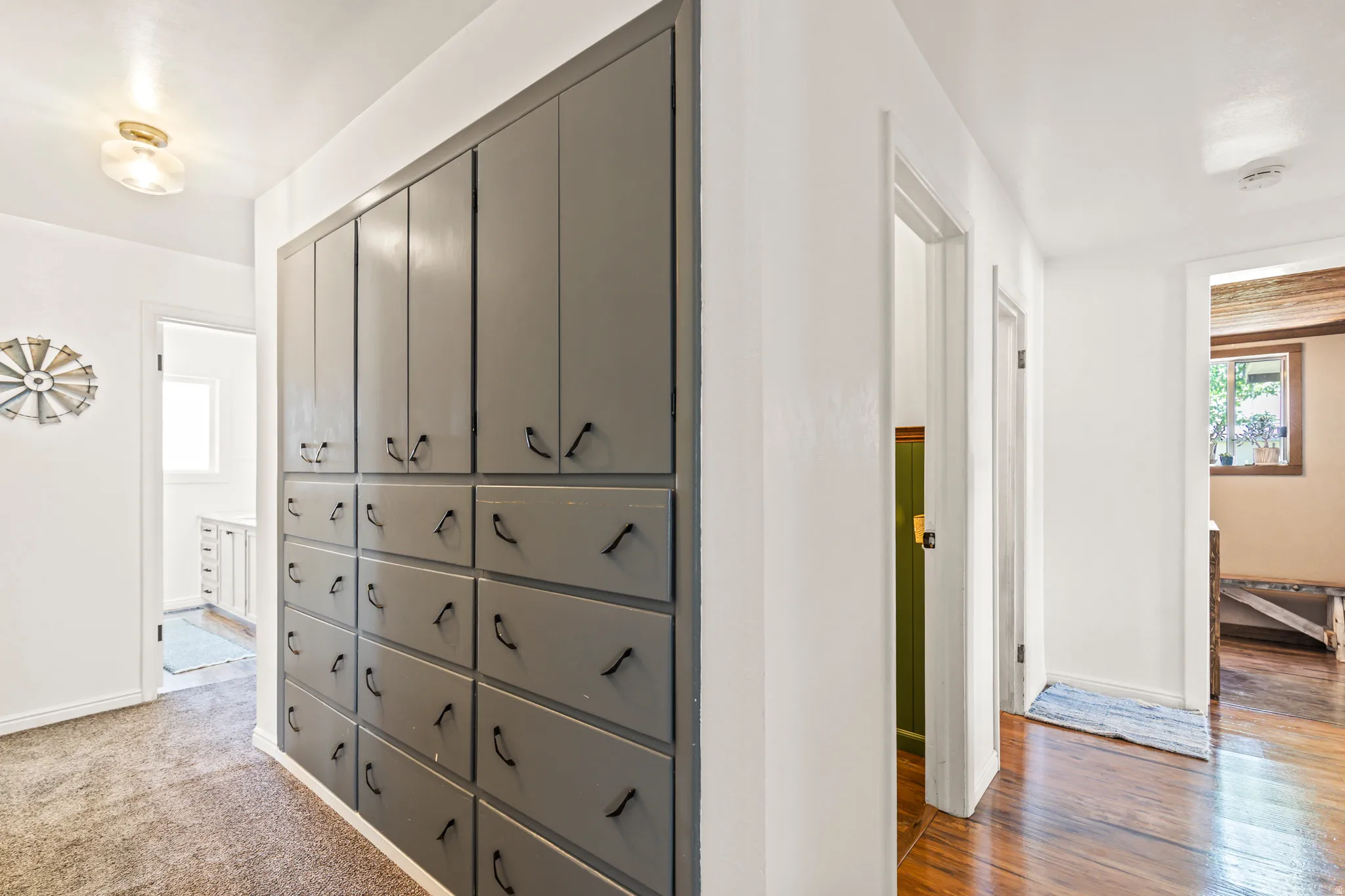 Hallway with built-in storage cabinetry featuring matte gray finishes and black hardware