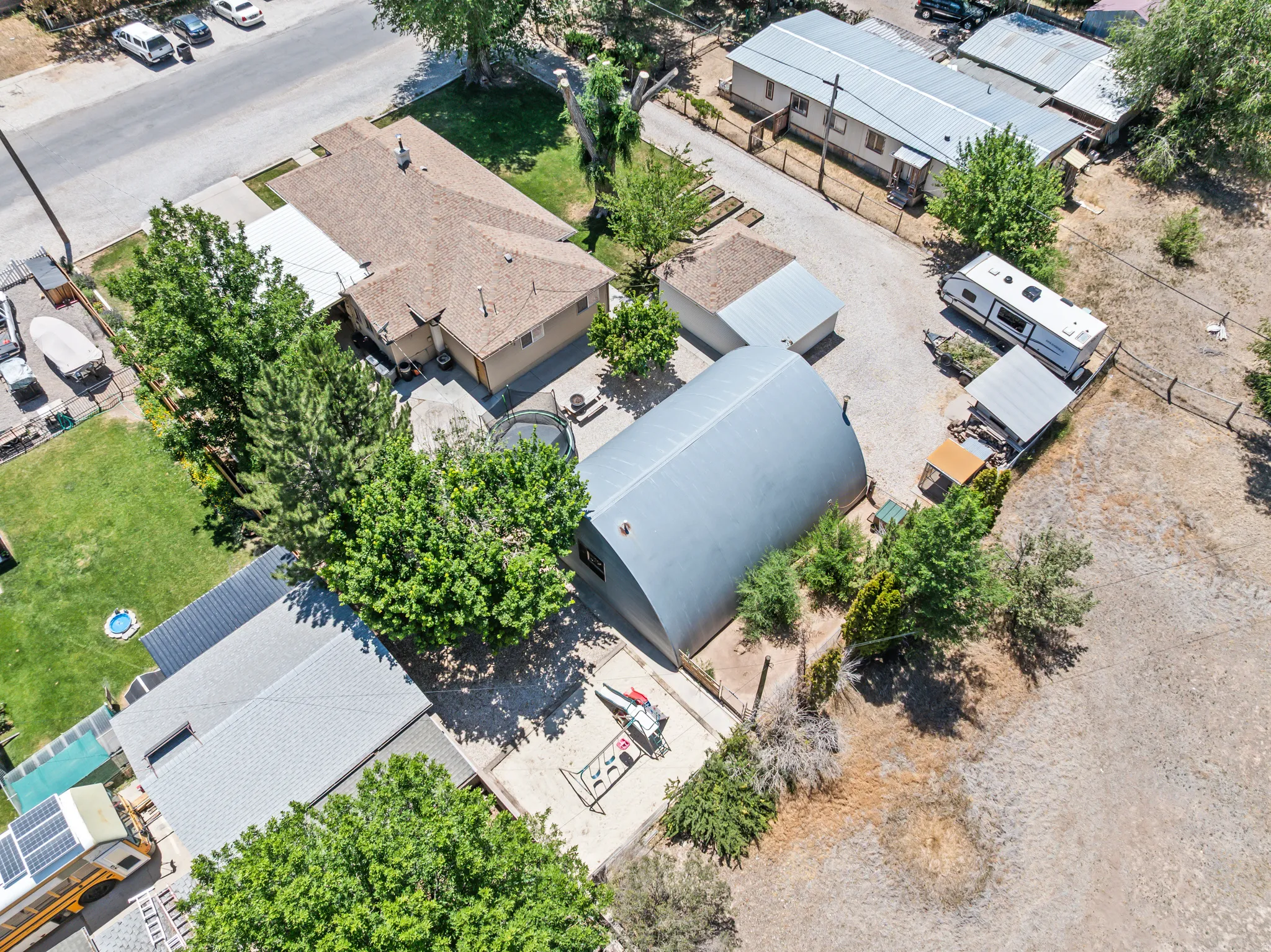Expansive property featuring multiple structures including a main residence with a brown shingle roof, a large quonset hut structure, and additional outbuildings