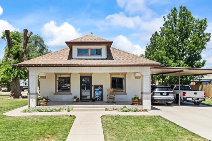 Front facade featuring a welcoming covered porch, dormer window, and a tan shingle roof