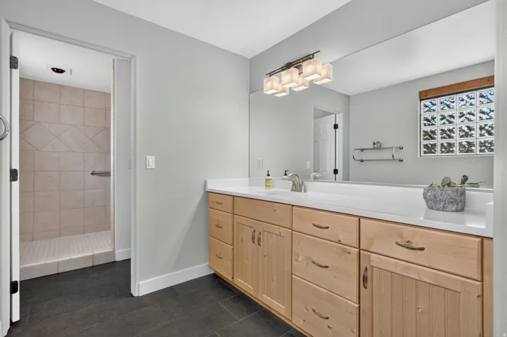 Extended vanity with integrated sink, light wood cabinetry, and a full-width mirror