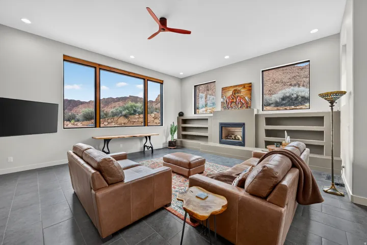 Expansive windows with wood trim, built-in fireplace with hearth, recessed lighting, and dark tile flooring