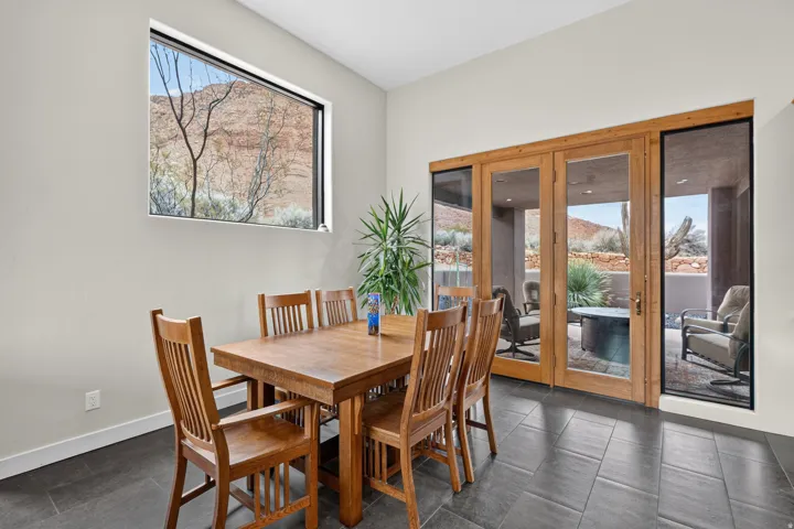 Sliding glass doors with wood frames, large picture window, stone tile flooring, high ceilings, and exterior patio access