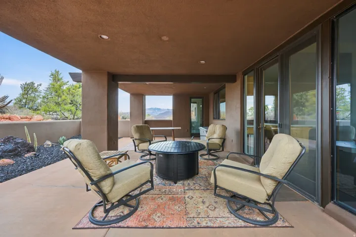 Covered outdoor patio with recessed lighting, large format sliding glass doors, and a decorative rock garden
