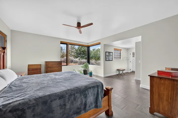 Corner window with dark wood framing, ceiling fan, and tile flooring