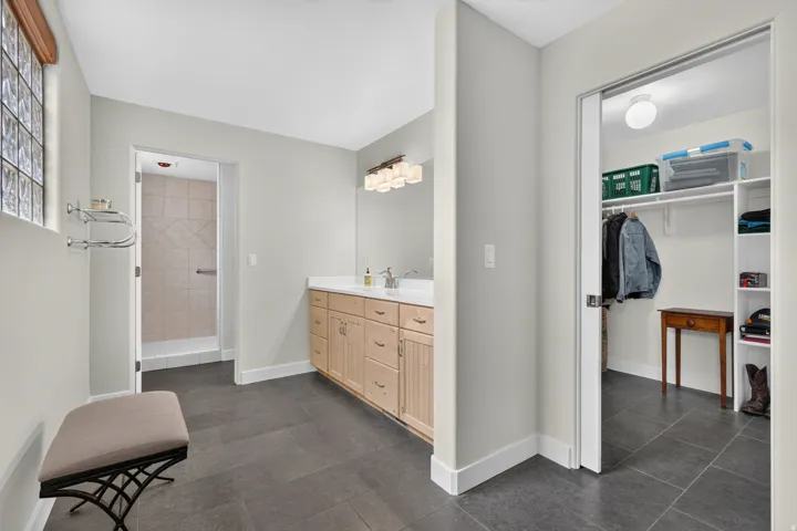 Dual vanity with light wood cabinetry, stone-look countertop, and undermount sinks