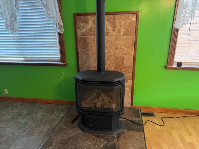 Freestanding black fireplace with a glass viewing door and visible logs
