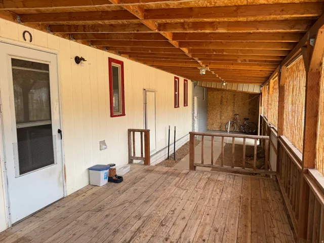 Expansive covered porch featuring wood-finish flooring, exposed wood beam ceiling, and a full-length screen door