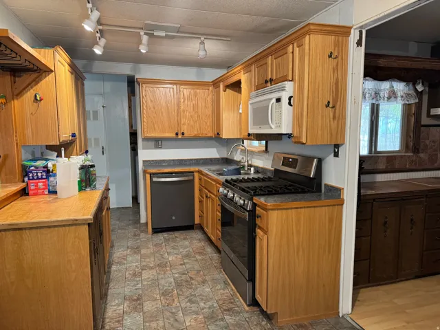 Kitchen featuring wood-finish cabinetry, track lighting, and a built-in microwave
