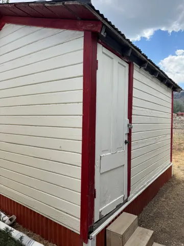 Utility building with horizontal siding and a corrugated metal foundation