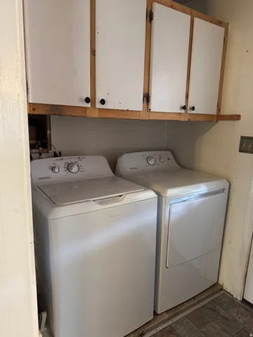 Dedicated laundry area featuring white upper cabinetry with wood trim and a tiled flooring surface