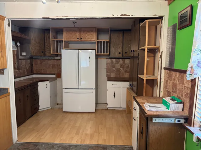 Kitchen space featuring wood-finish flooring, a white French door refrigerator, and a mix of wood cabinetry