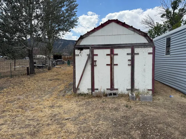 White storage shed with a gambrel roof and red trim