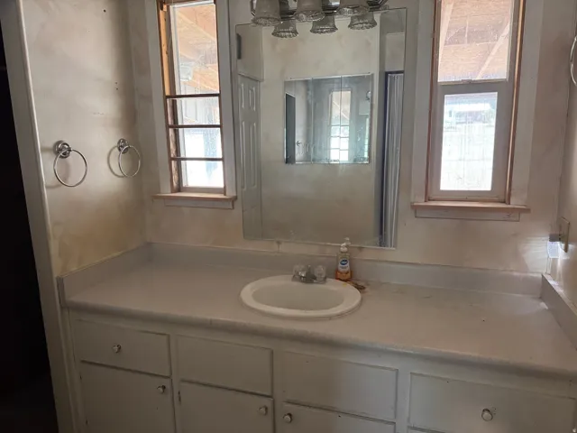 Bathroom vanity with integrated sink, flanked by two windows