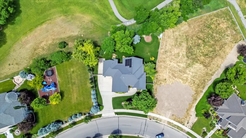 Expansive property featuring a large residential structure with a multi-gabled roof, mature landscaping, a manicured lawn, and a paved driveway