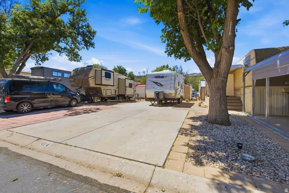 Concrete parking pad with brick paver accents and an adjacent gravel landscaping bed