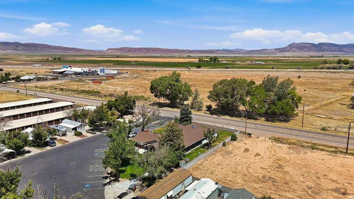 Expansive undeveloped land featuring a paved road, mature trees, and mountainous terrain in the distance