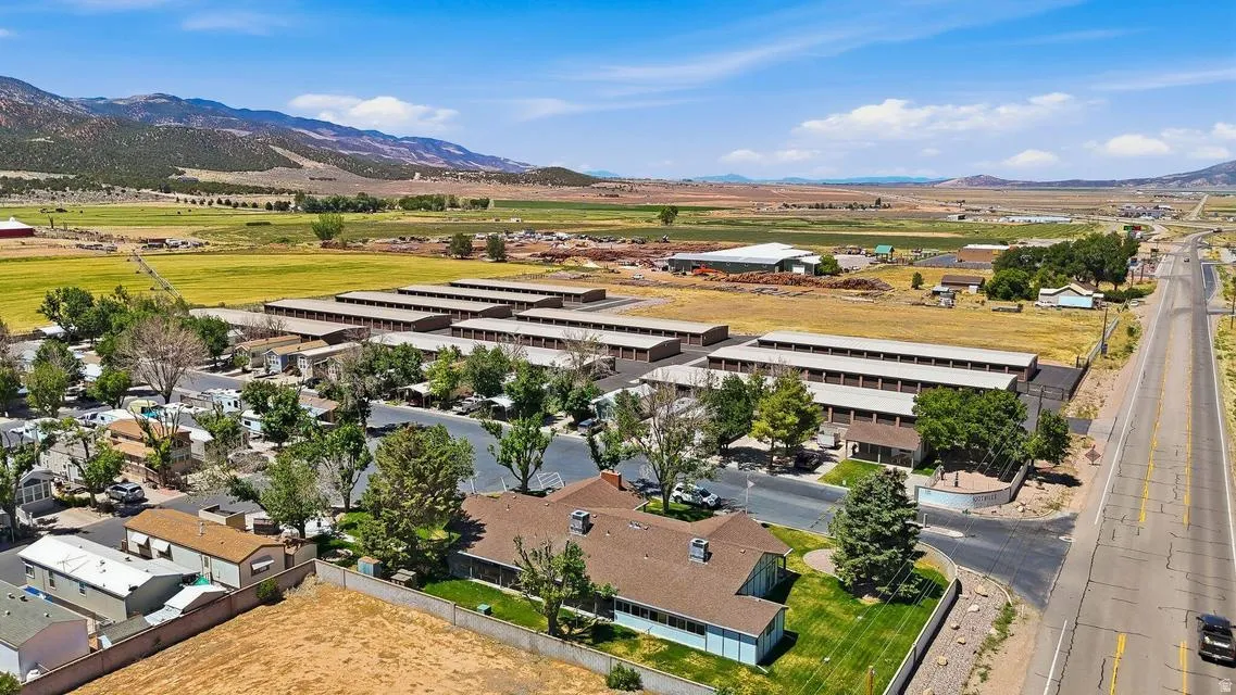 Expansive property featuring multiple storage unit buildings, a multi-unit residential structure, and a large paved parking area
