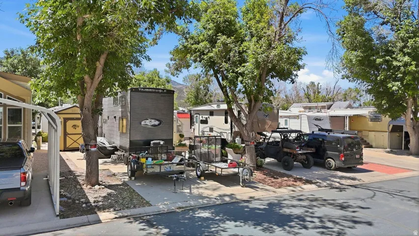Paved parking area featuring mature trees providing shade