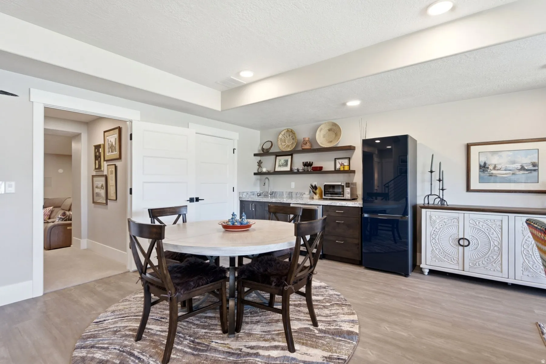 Recessed lighting illuminates a well-appointed wet bar featuring open shelving, a built-in sink, and wood-finish cabinetry