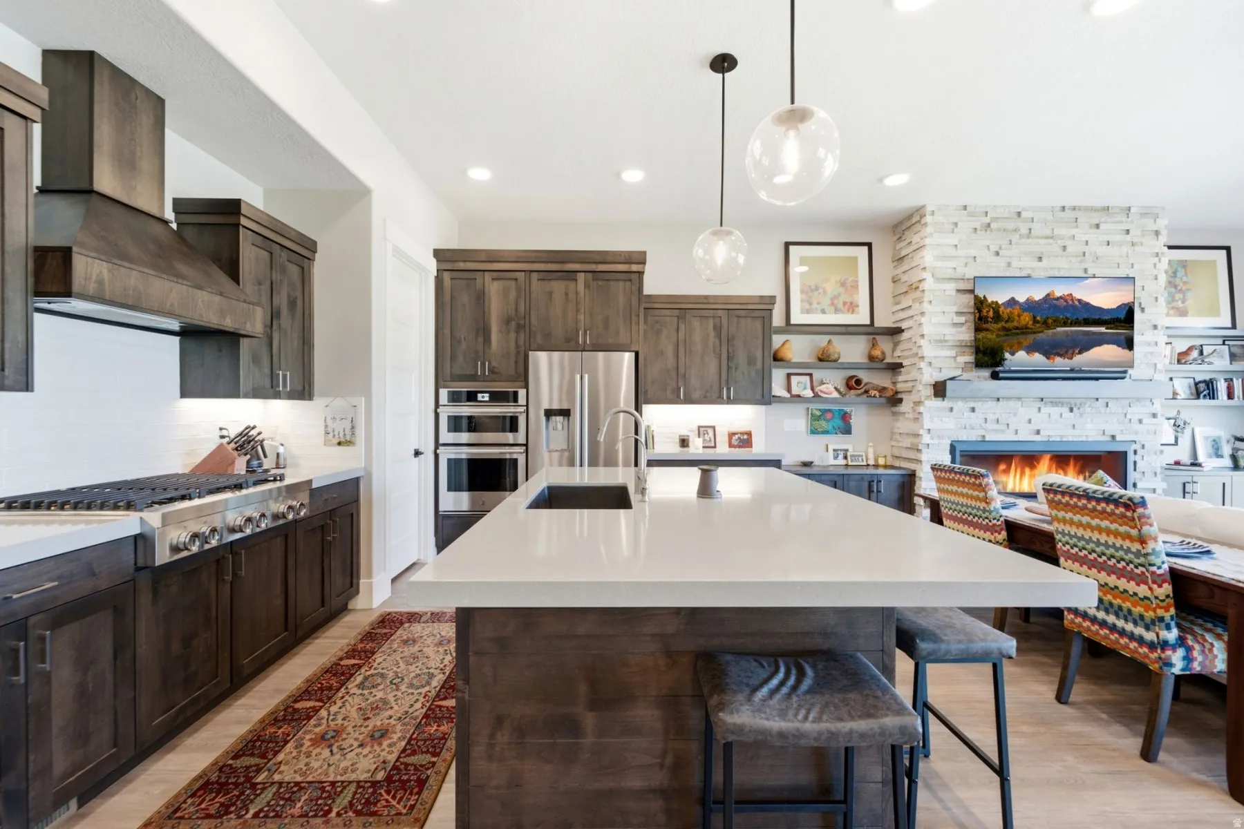 Gourmet kitchen featuring a large island with seating, stainless steel appliances, a gas range with a custom wood hood, and recessed lighting