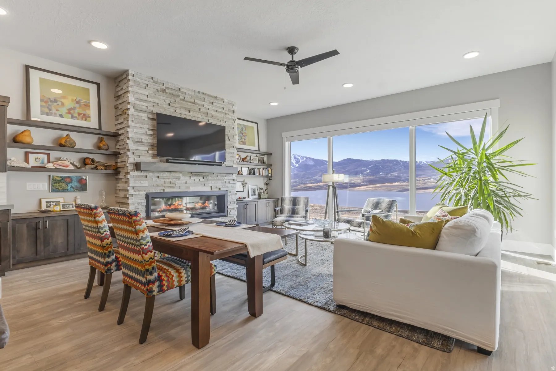 Contemporary living space featuring expansive glass doors, a floor-to-ceiling stacked stone fireplace with a linear insert, and recessed lighting