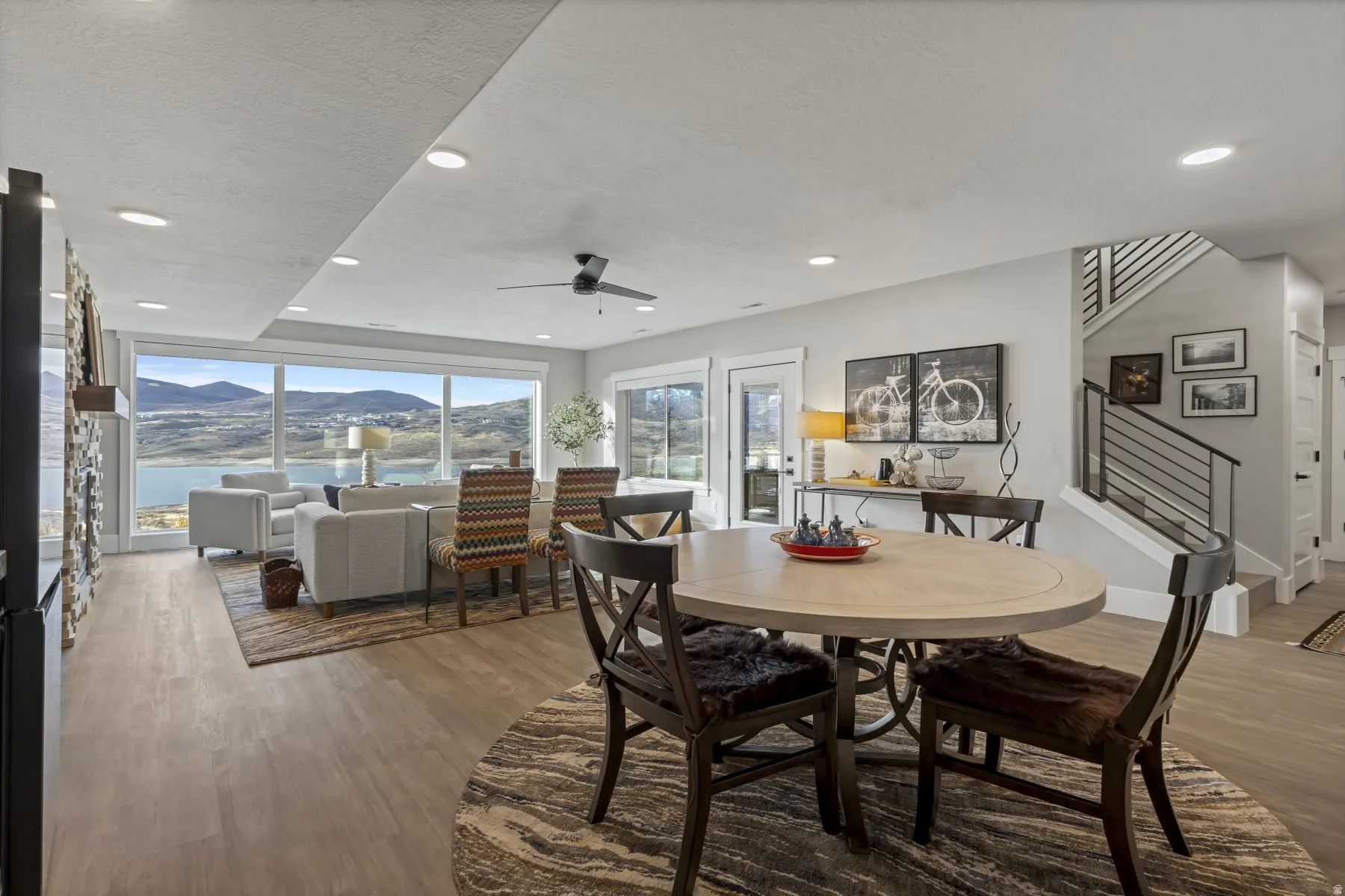 Open-concept living area featuring expansive glass doors and windows, offering panoramic water and mountain scenery