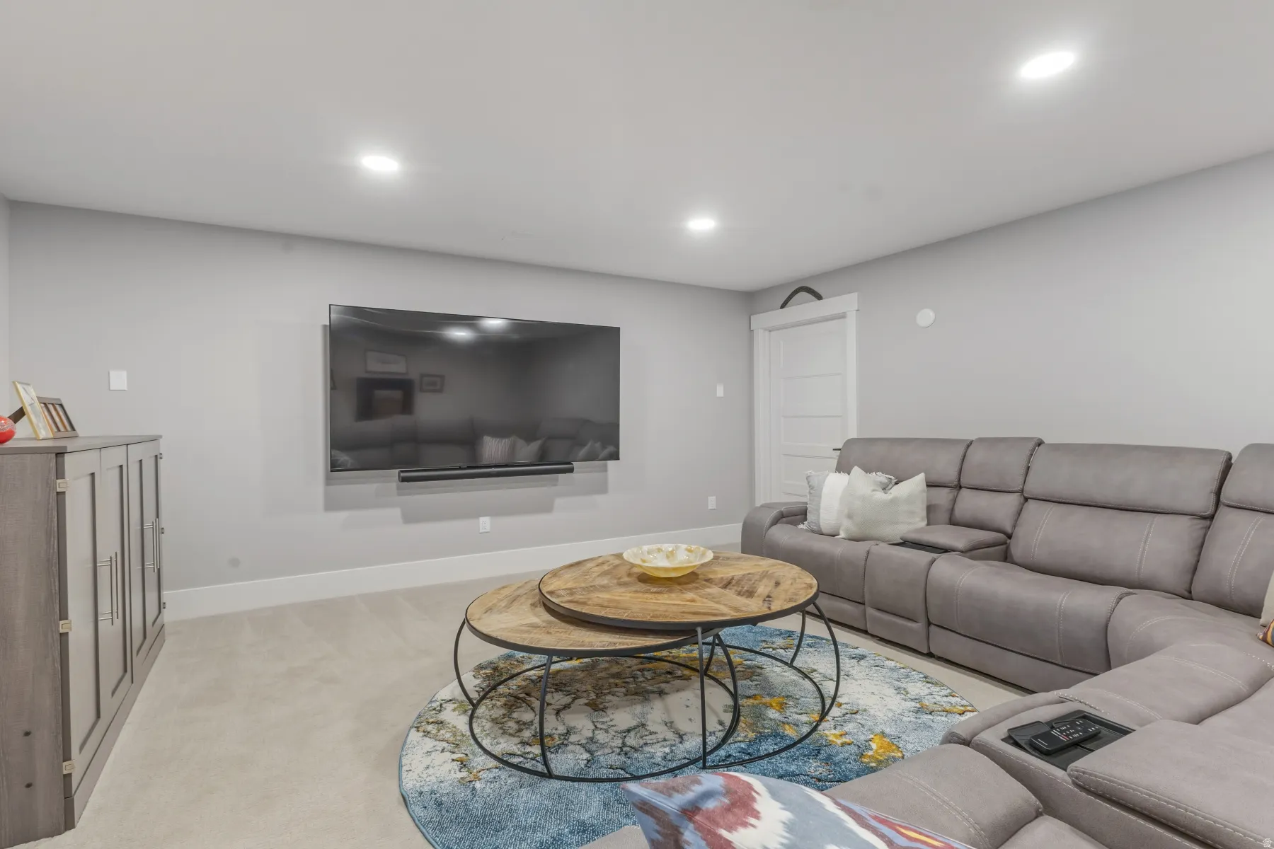 Spacious living area featuring light gray walls, recessed lighting, and soft carpeting
