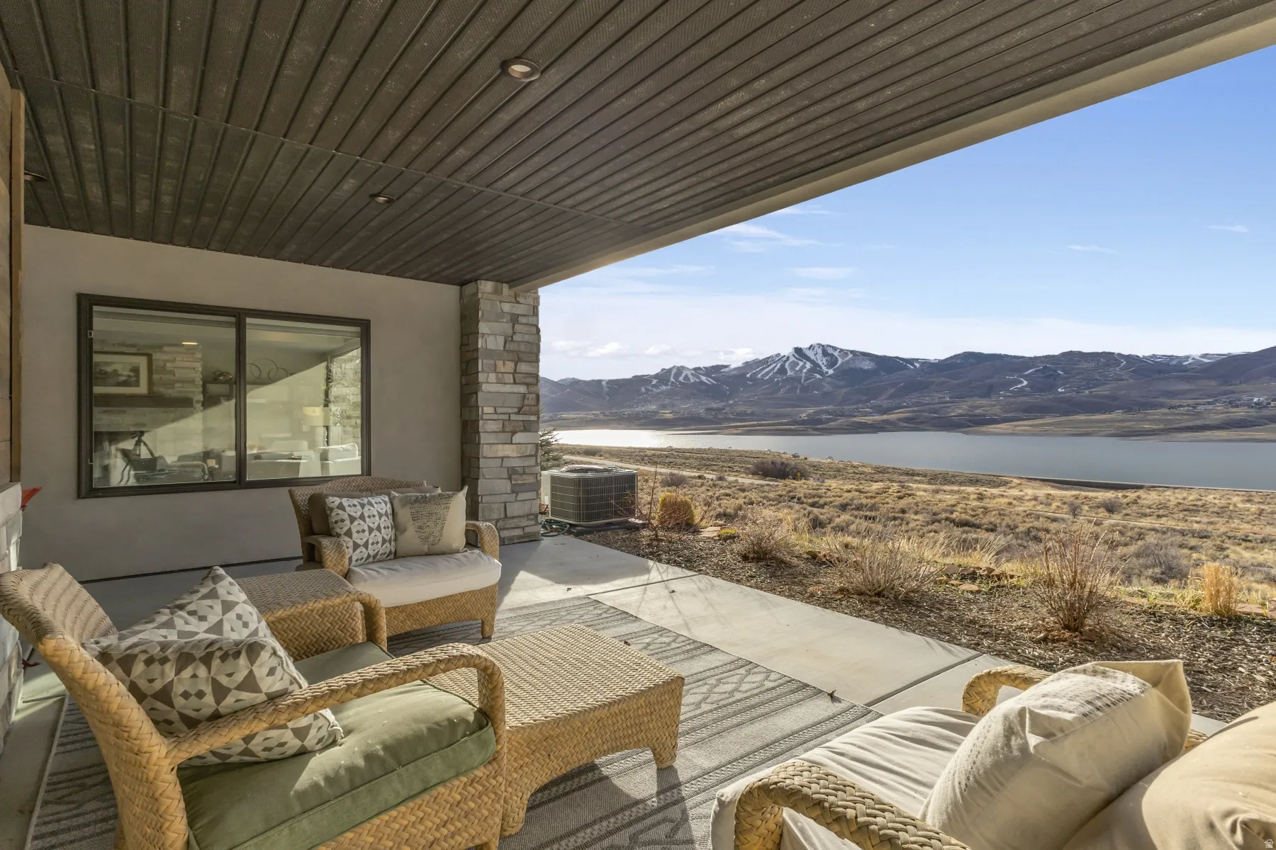 Covered patio with a concrete surface, stone accents, and a slatted ceiling