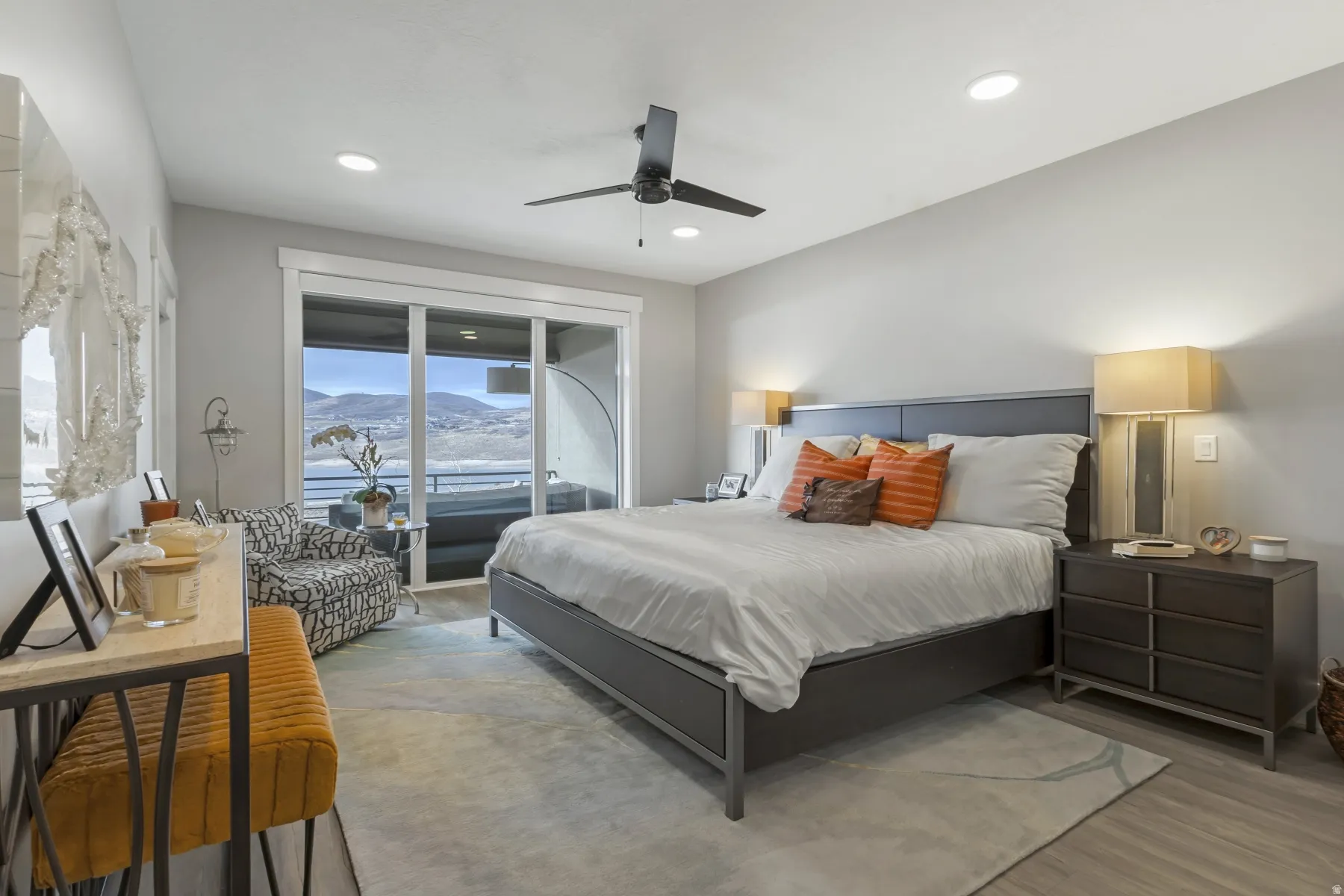 Spacious bedroom featuring wood-finish flooring, a contemporary ceiling fan, recessed lighting, and a large sliding glass door opening to an outdoor area