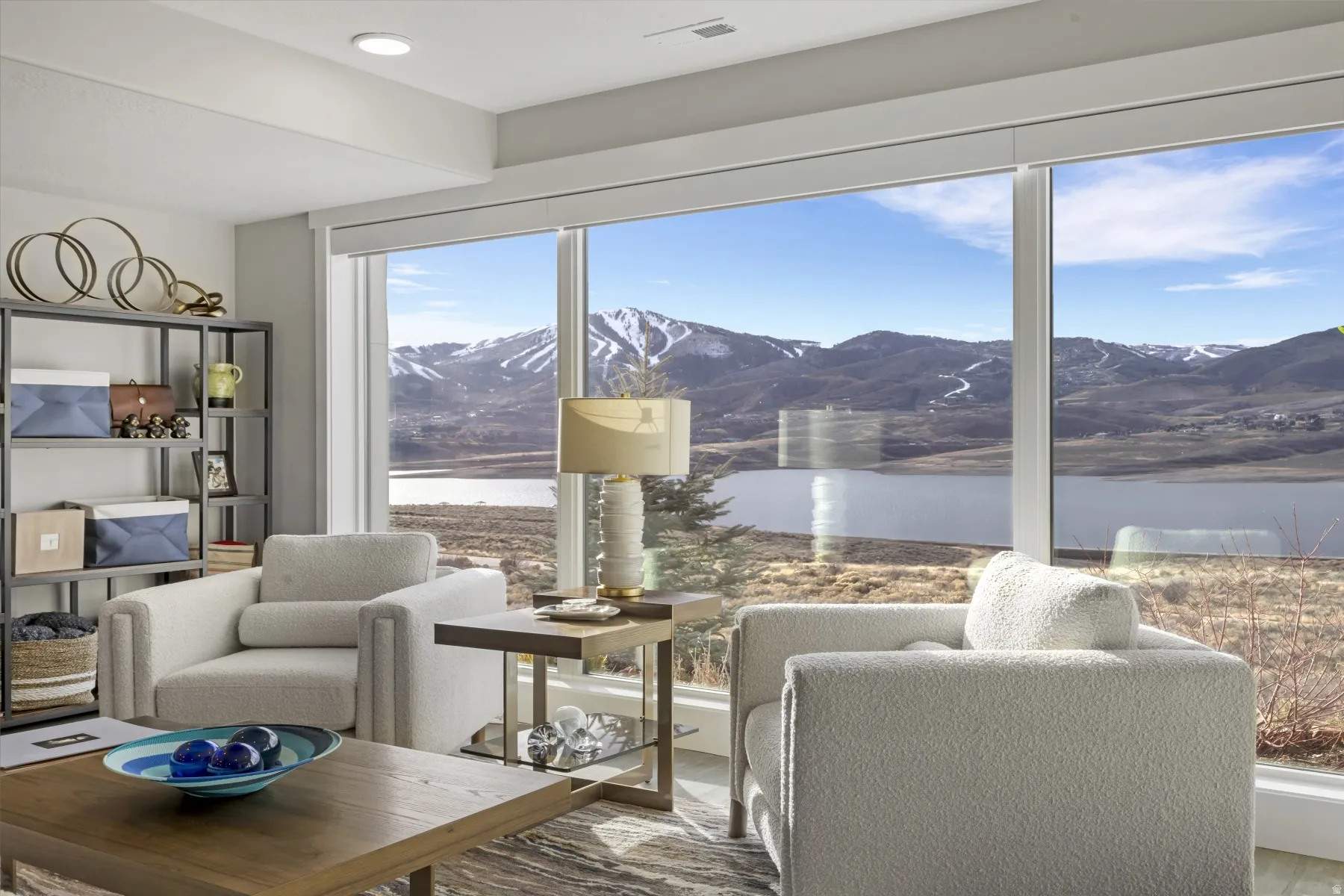 Floor-to-ceiling windows frame expansive water and mountain scenery