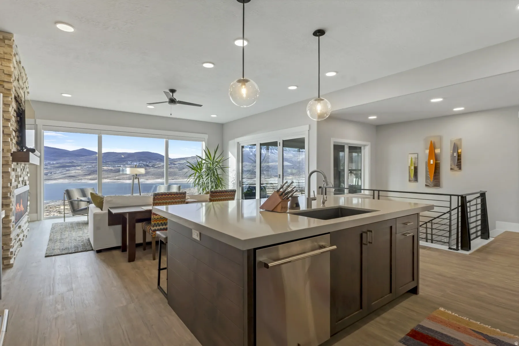 Open-concept living space featuring a central kitchen island with integrated sink, stainless steel dishwasher, and two pendant lights