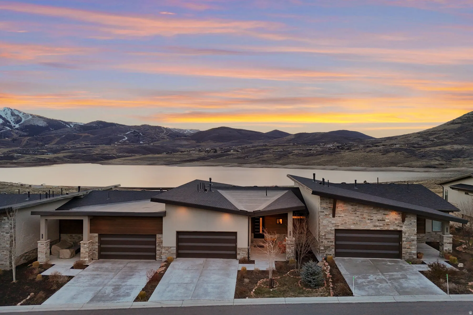 Modern property featuring a sleek, angular roofline and a combination of stucco and stone veneer exterior