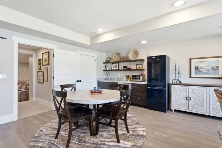 Recessed lighting illuminates a well-appointed wet bar featuring open shelving, a built-in sink, and wood-finish cabinetry