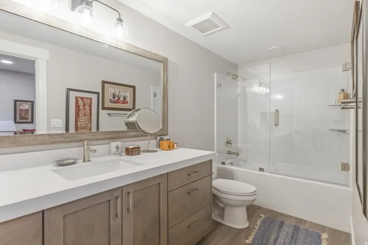 Contemporary bathroom featuring a spacious vanity with integrated sink, light wood-finish cabinetry, and a full-width mirror