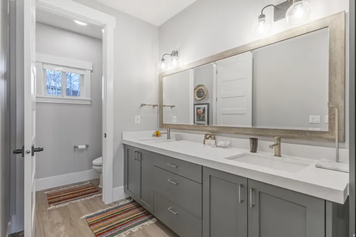 Dual vanity with integrated sinks, brushed nickel fixtures, and a large framed mirror