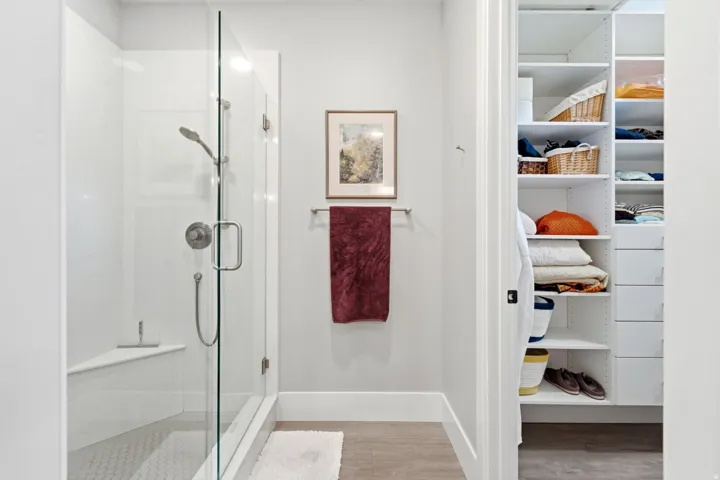 Glass-enclosed shower with a built-in bench, hexagon tile flooring, and brushed nickel fixtures