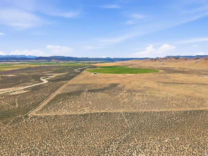 Expansive land parcel featuring natural topography, distant mountains, and a circular green field
