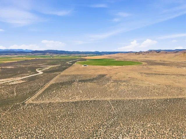 Expansive land parcel featuring natural topography, distant mountains, and a circular green field