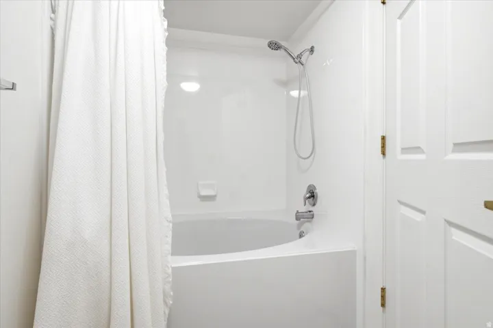 White tub and shower combination with a curved basin and integrated soap dish