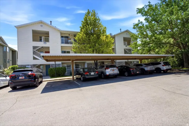 Multi-level residential building featuring a carport structure and exterior stair access