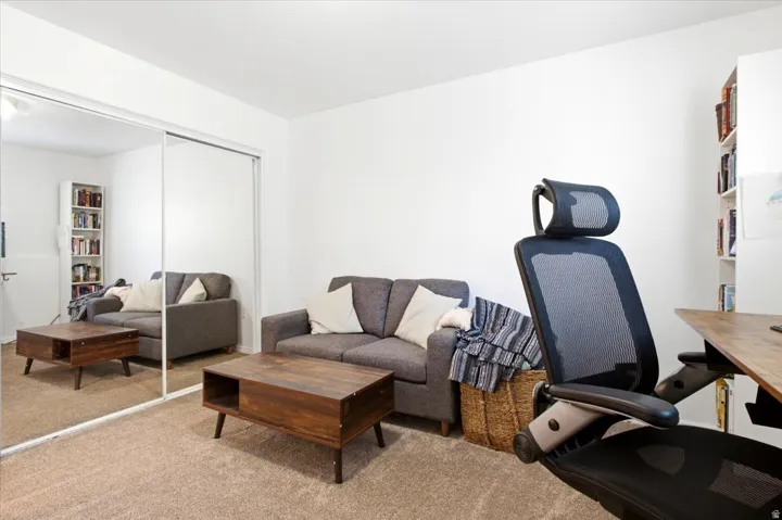 Wall-to-wall mirrored sliding closet doors define this room, featuring light tan carpeting and white walls