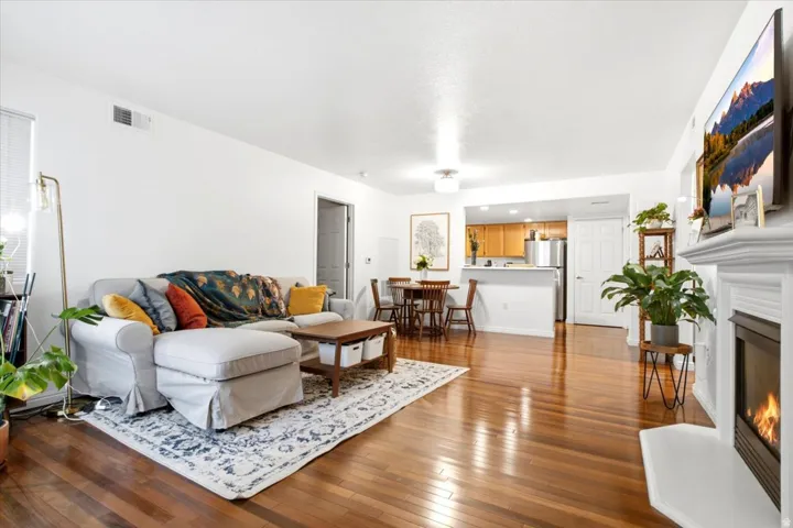 Open-concept living space featuring wood-finish flooring, a built-in fireplace with a substantial mantel, and recessed lighting